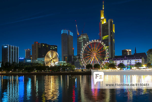 Das traditionelle Mainfest mit Fahrgeschäften und Riesenrad vor der Frankfurter Skyline  vom südlichen Mainufer aus gesehen