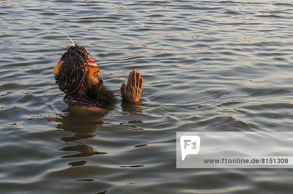 Sadhu  holy man  taking a bath and praying in the Sangam  the confluence of the rivers Ganges  Yamuna and Saraswati  just before sunset  Kumbha Mela mass Hindu pilgrimage