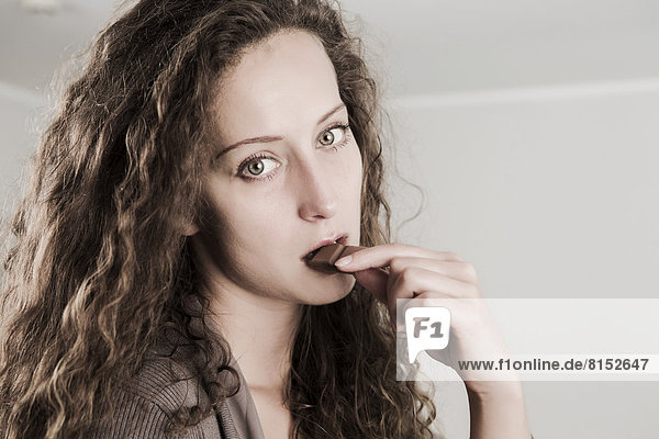 Junge Frau isst einen Riegel Schokolade