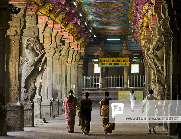 Visitors in the temple hall with brightly painted pillars  mythical creatures  Meenakshi Amman Temple or Sri Meenakshi Sundareswarar Temple