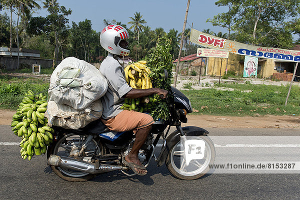 Mann auf mit Bananen beladenem Motorrad