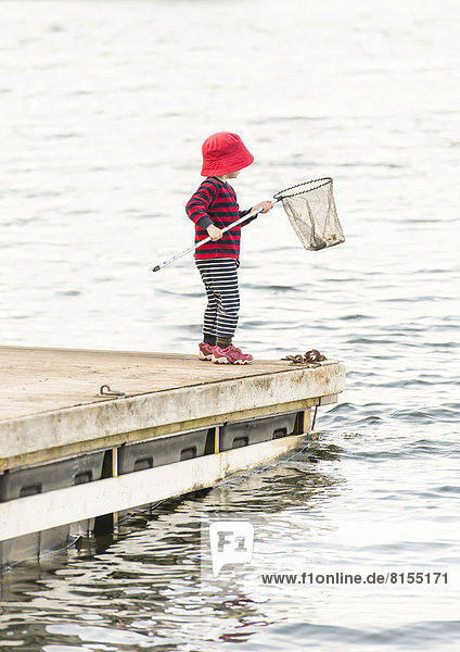 Child standing on jetty  holding dip net