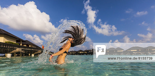 Malediven  Junge Frau spritzt nasses Haar in der Lagune