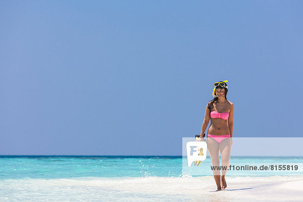 Malediven  junge Frau  die am Strand spazieren geht.