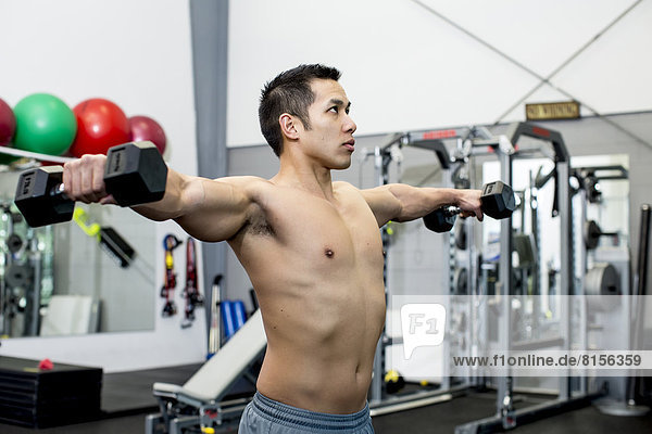 Pacific Islander man lifting weights in gym