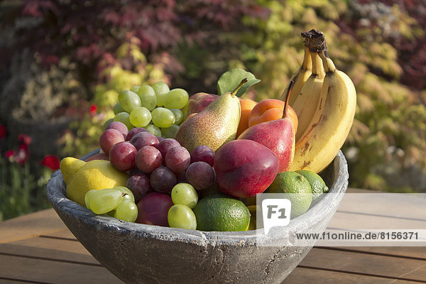 Germany  Rhineland Palatinate  Bowl of fruits on wooden table  close up