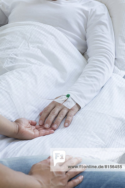 Woman holding hand of man in hospital,  close up