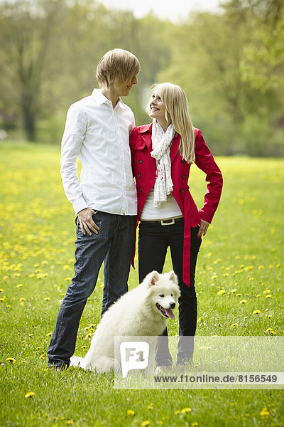 Germany  Young couple looking at each other with dog  smiling