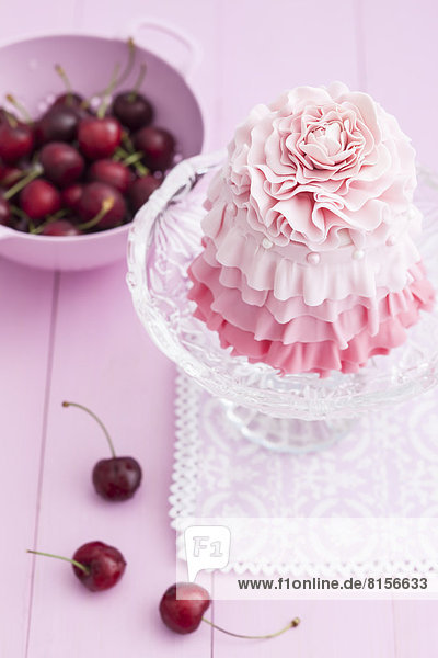 Rosa Mini-Kuchen auf Kuchenständer mit Kirschen