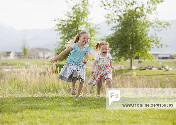 Caucasian girls running in grass