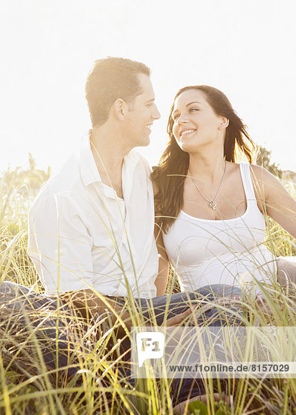 Caucasian couple sitting in tall grass