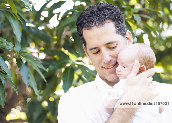 Caucasian father holding baby outdoors