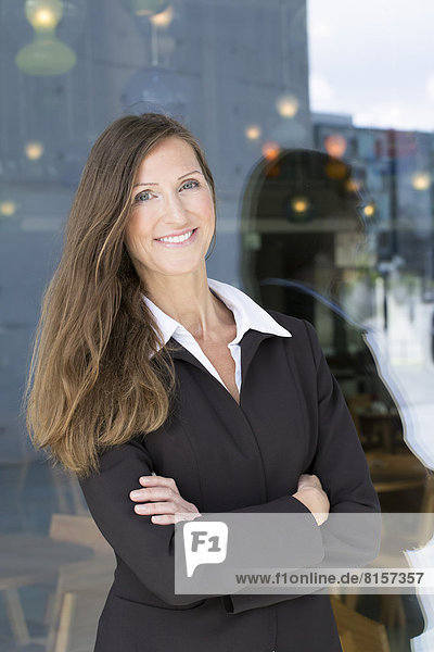 Portrait of businesswoman leaning against wall  smiling