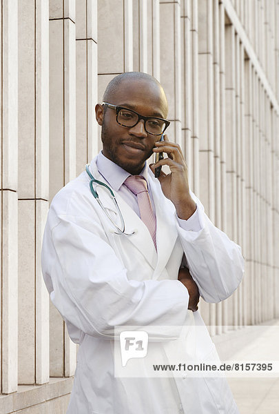 Black doctor talking on cell phone on city street