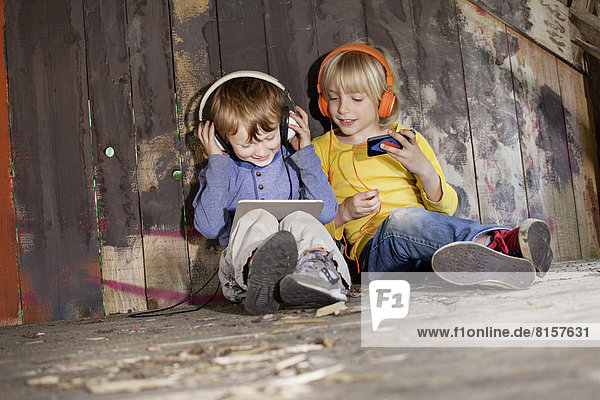Germany  North Rhine Westphalia  Cologne  Boys listening music in playground  smiling