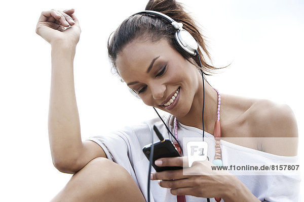Germany  Young woman listening music with head phones  smiling