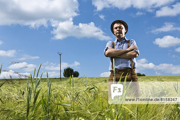 Germany  Bavaria  Farmer standing with arms crossed in field
