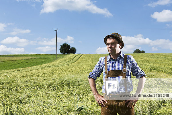 Germany  Bavaria  Farmer standing in field and looking away
