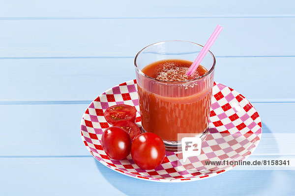 Frischer Tomatensaft im Glas mit Tomaten im Teller  Nahaufnahme