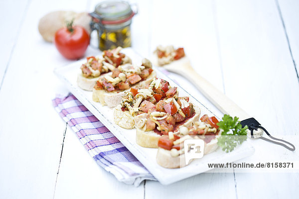 Plate of bruschetta with tomatoes  white shimeji mushrooms  herbs and olive oil on wooden table  close up