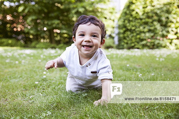Baby boy crawling on grass  smiling