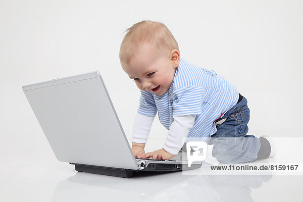 Baby boy using laptop on white background  smiling
