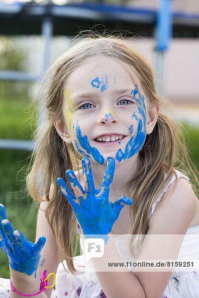 Portrait of girl playing with finger paint  smiling