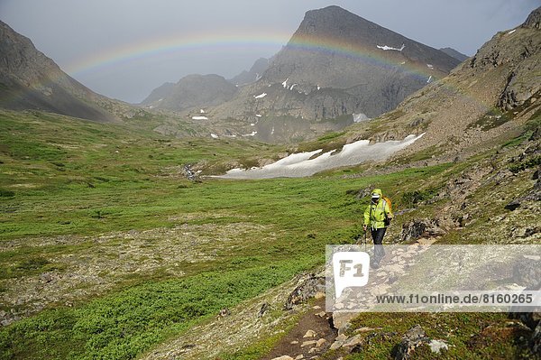 Backpacker hiking under a rainbow in Chugach State Park near Anchorage  Alaska.