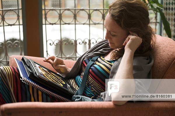 A woman relaxing with her Ipad in the elaborate lobby of the riad (small hotel) Dar El Ghalia in Fes el-Bali  Fes  Morocco.