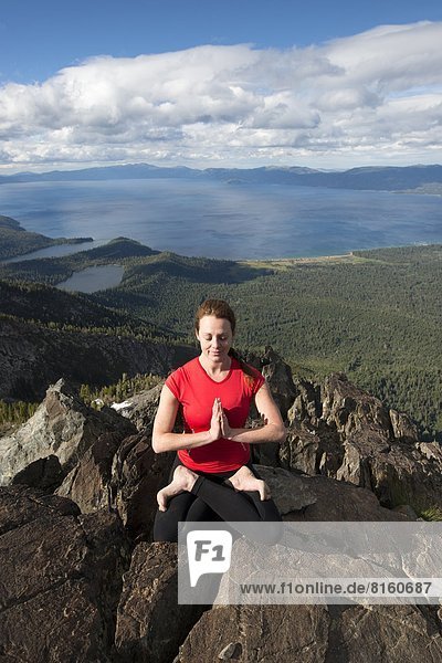 A woman performs yoga on top of Mount Tallac overlooking Lake Tahoe on a beautiful afternoon near South Lake Tahoe  CA.