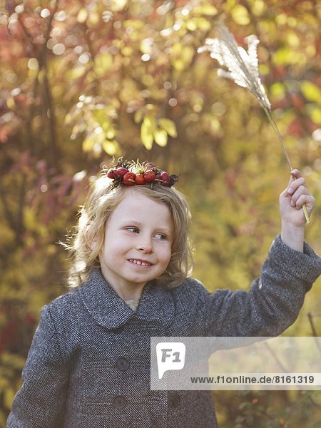 Girl wearing rose hip wreath holding autumn leaf