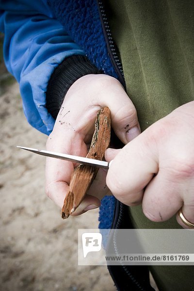 Hands whittling wood