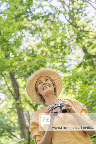 Senior woman with binoculars in park