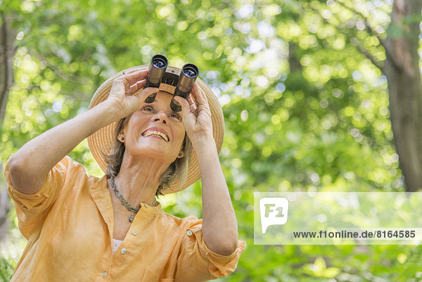 Senior woman with binoculars in park