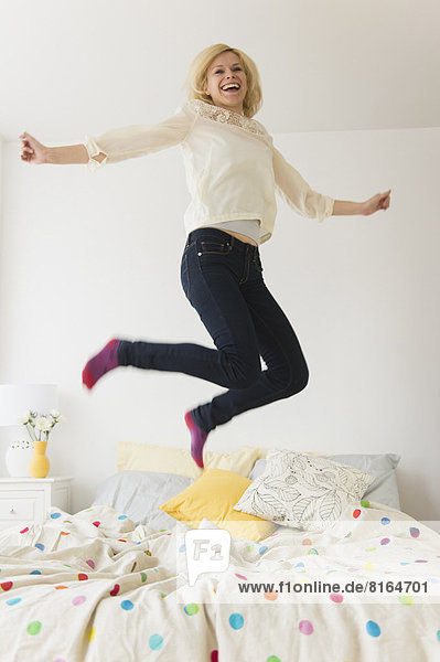 Junge Frau springen auf Bett