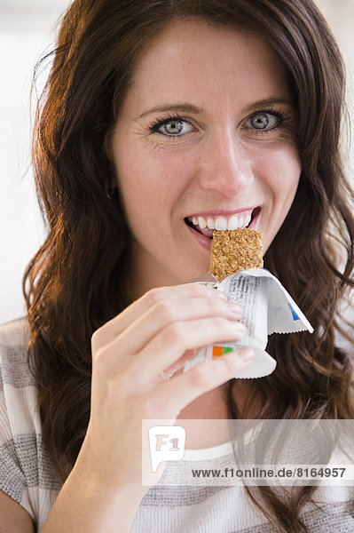 Portrait of young woman eating granola bar
