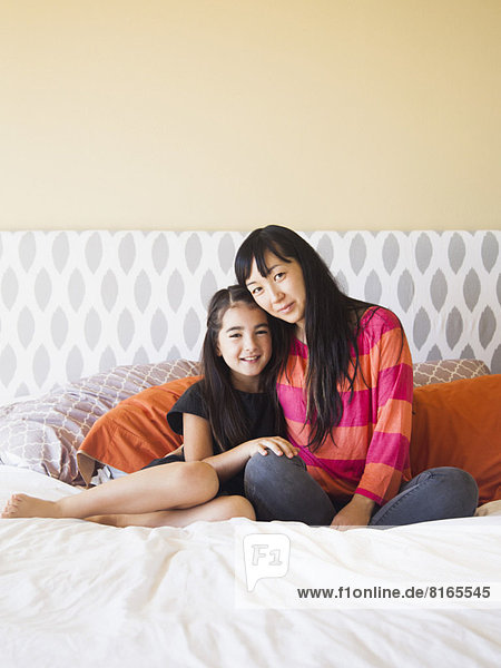 Mother with daughter (8-9) sitting on bed