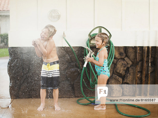 Children (2-3  6-7) refreshing with garden hose