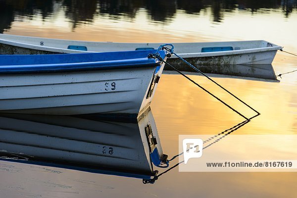 Rowboat floating on lake at sunset