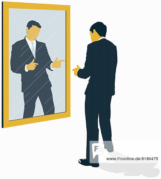 Confident businessman looking at reflection and pointing in mirror