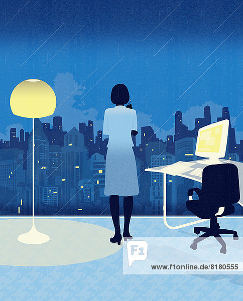 Businesswoman working late and looking out of office window at city at night