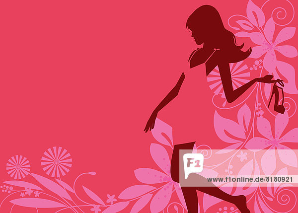 Glamouröse Frau hält einen High Heel vor pinkfarbenem Blumenmuster