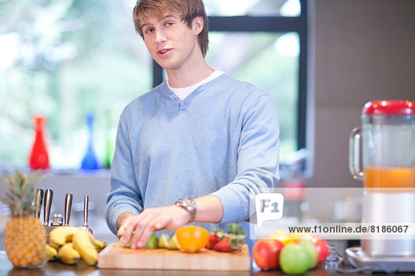 Junger Mann in der Küche beim Zubereiten von Fruchtgetränken