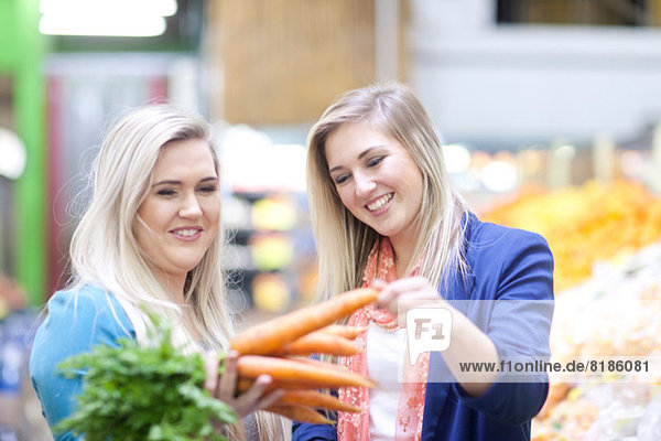 Zwei junge Frauen bei der Gemüsekontrolle auf dem Indoor-Markt