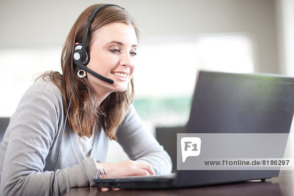 Young woman wearing headset using computer