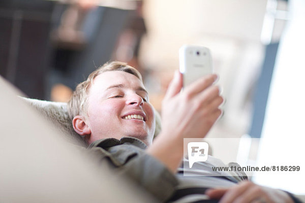 Man lounging on sofa looking at cellphone