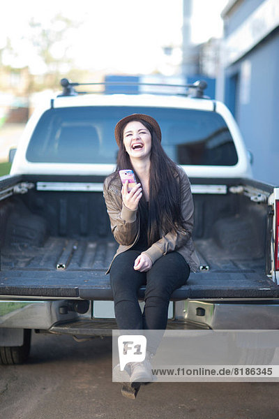 Porträt einer jungen Frau  die auf dem Rücken eines Lastwagens sitzt