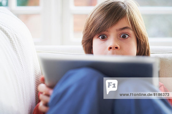 Junge auf Sofa mit digitalem Tablett