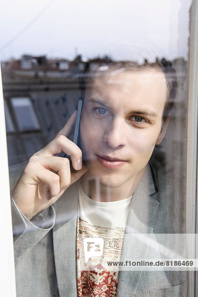Mann auf dem Handy hinter dem Fenster