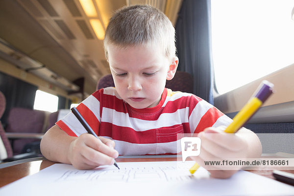 Junge mit Bleistift  Feder und Papier im Zug